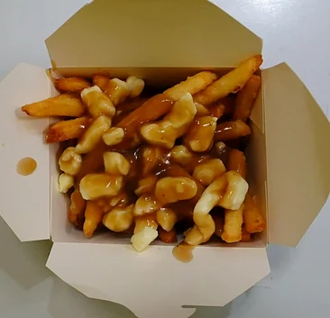 Classic poutine with fries, cheese curds and brown gravy in a takeout box