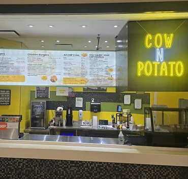 Cow N Potato Food Bar counter in the Northgate Mall food court with its neon sign