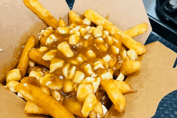 Poutine with fries, cheese curds and gravy in an open kraft takeout box